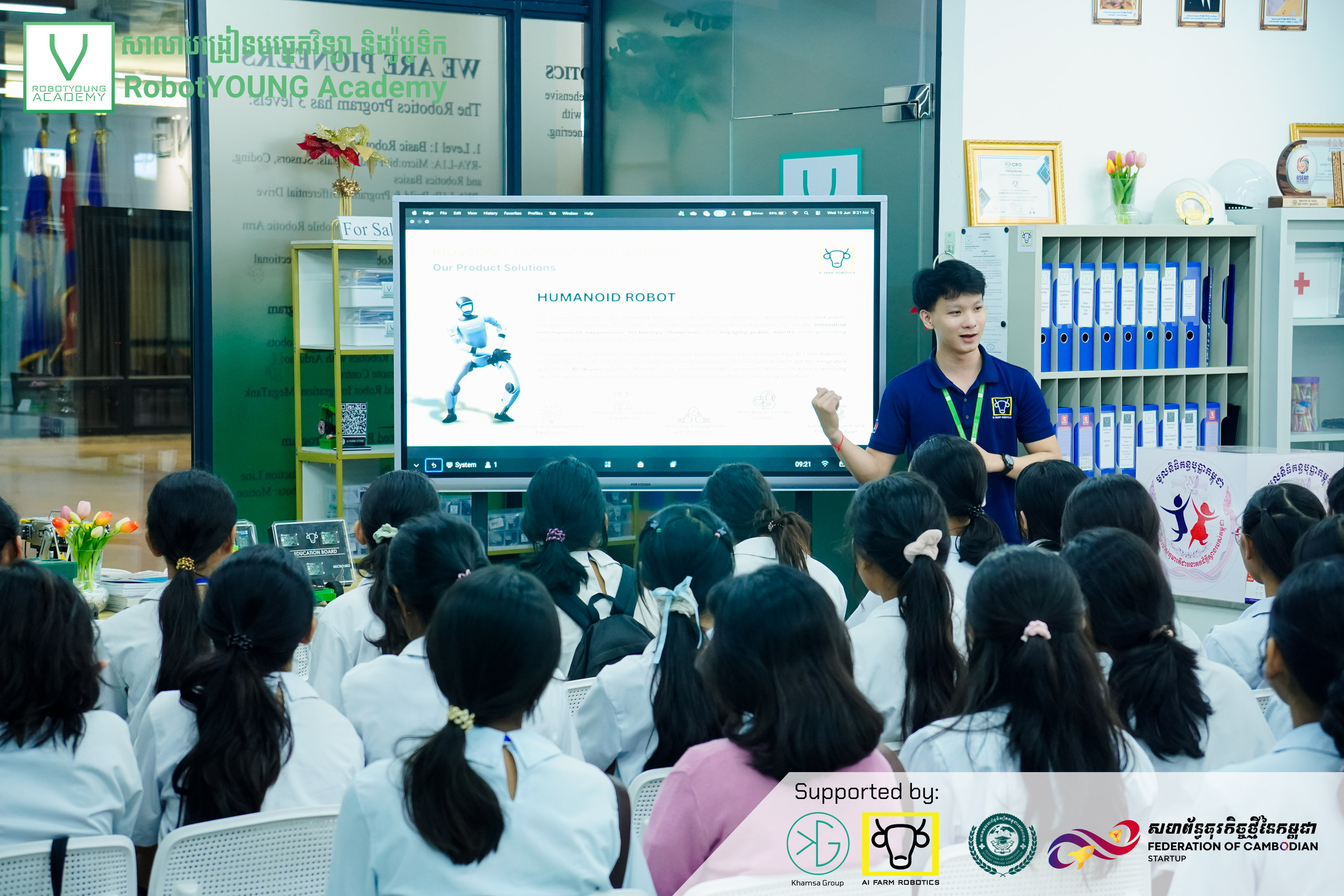 A presenter discussing a humanoid robot slide with a seated student audience