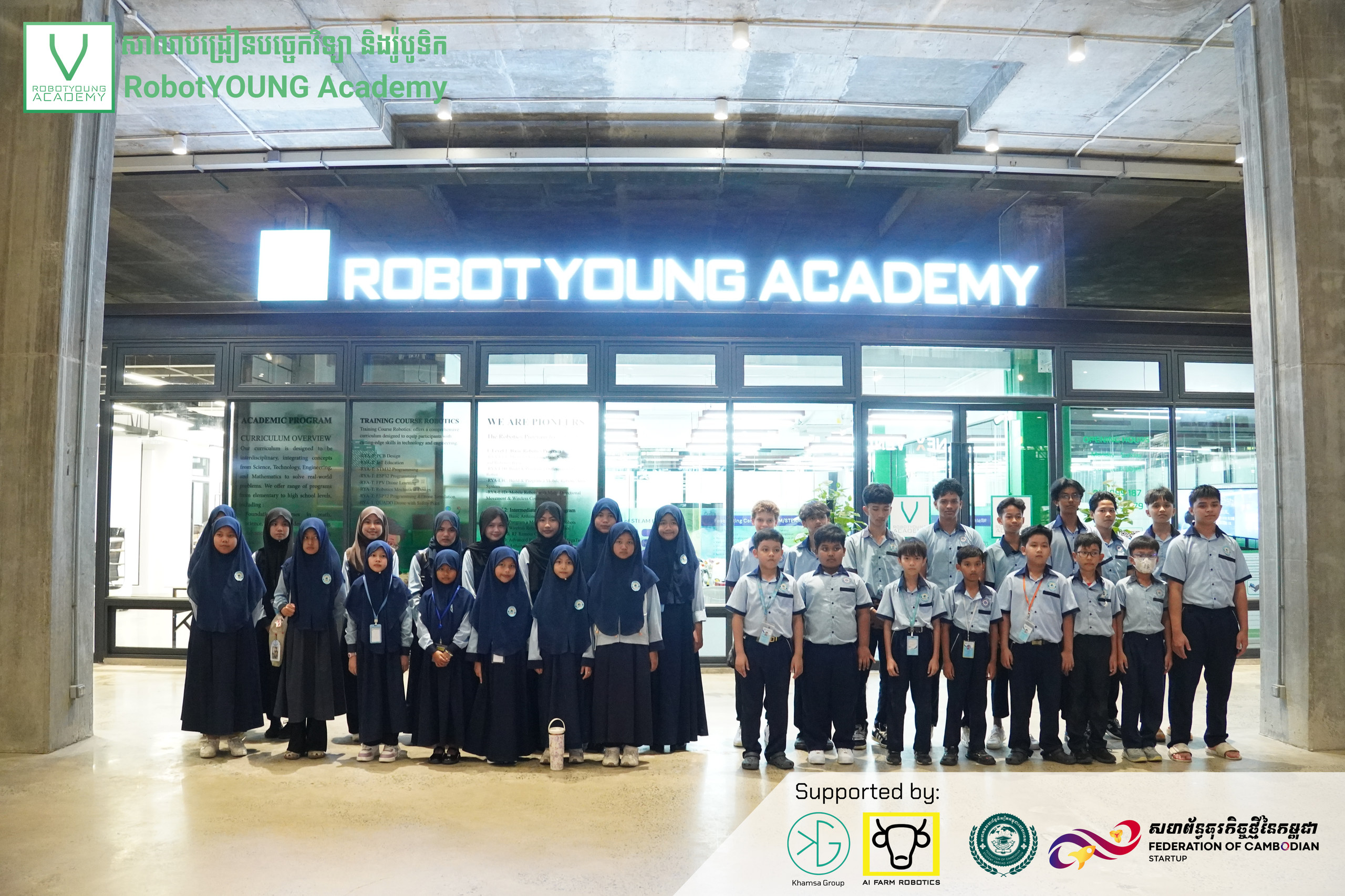 A visiting group posing beneath the illuminated RobotYOUNG Academy entrance sign