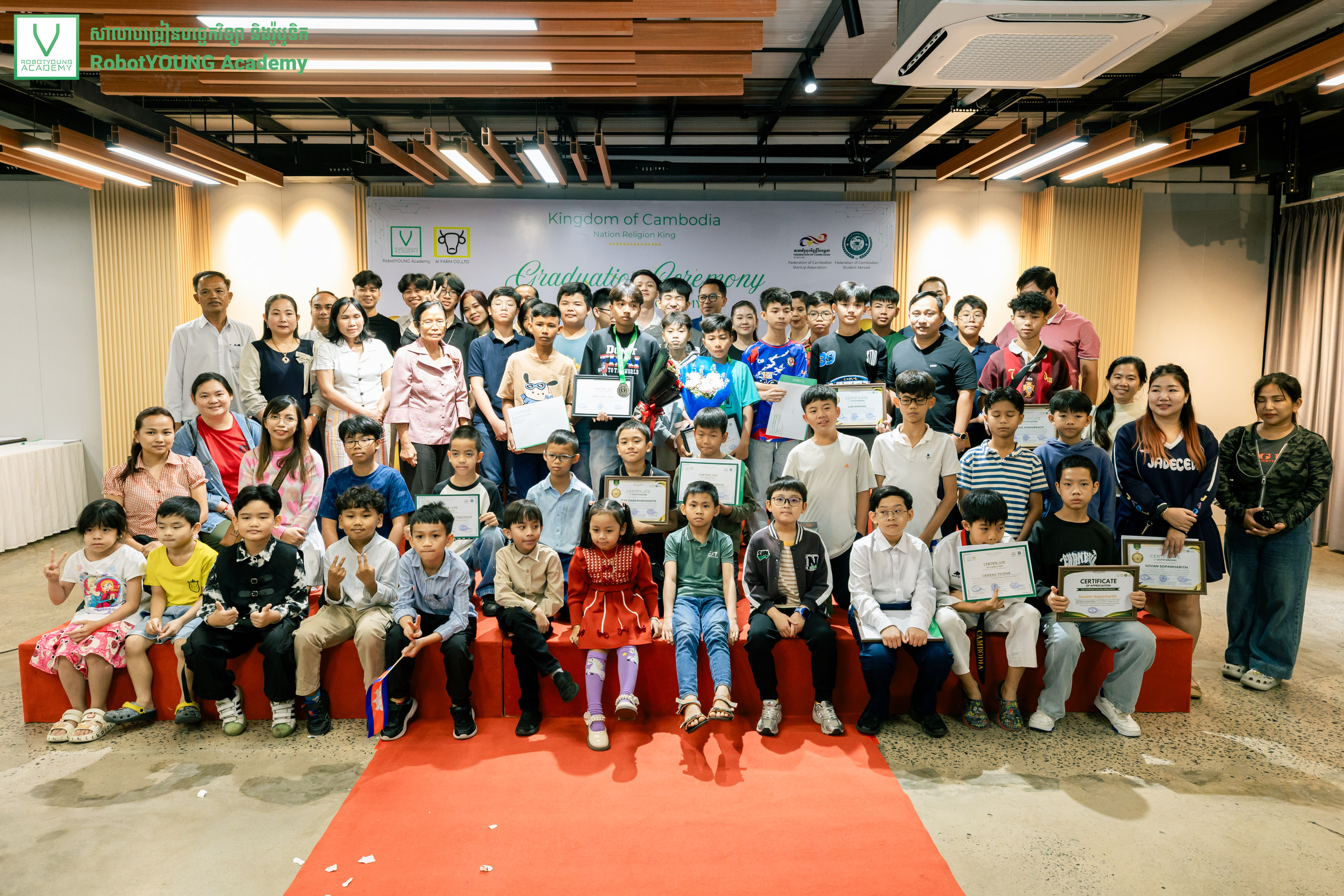 Children, teenagers and adults posing with certificates, medals and bouquets at a graduation ceremony