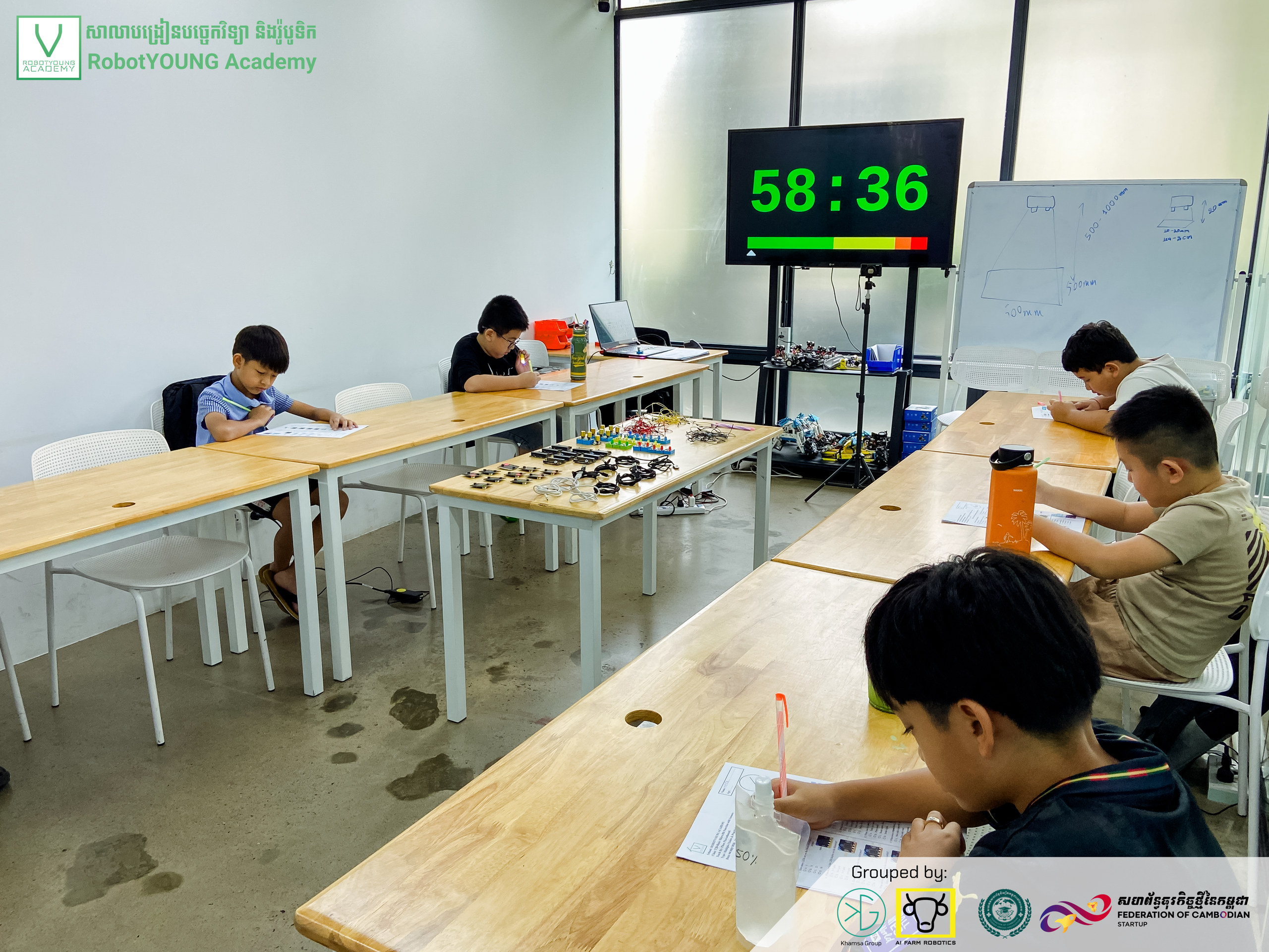 Students working at separate classroom tables beneath a digital countdown display