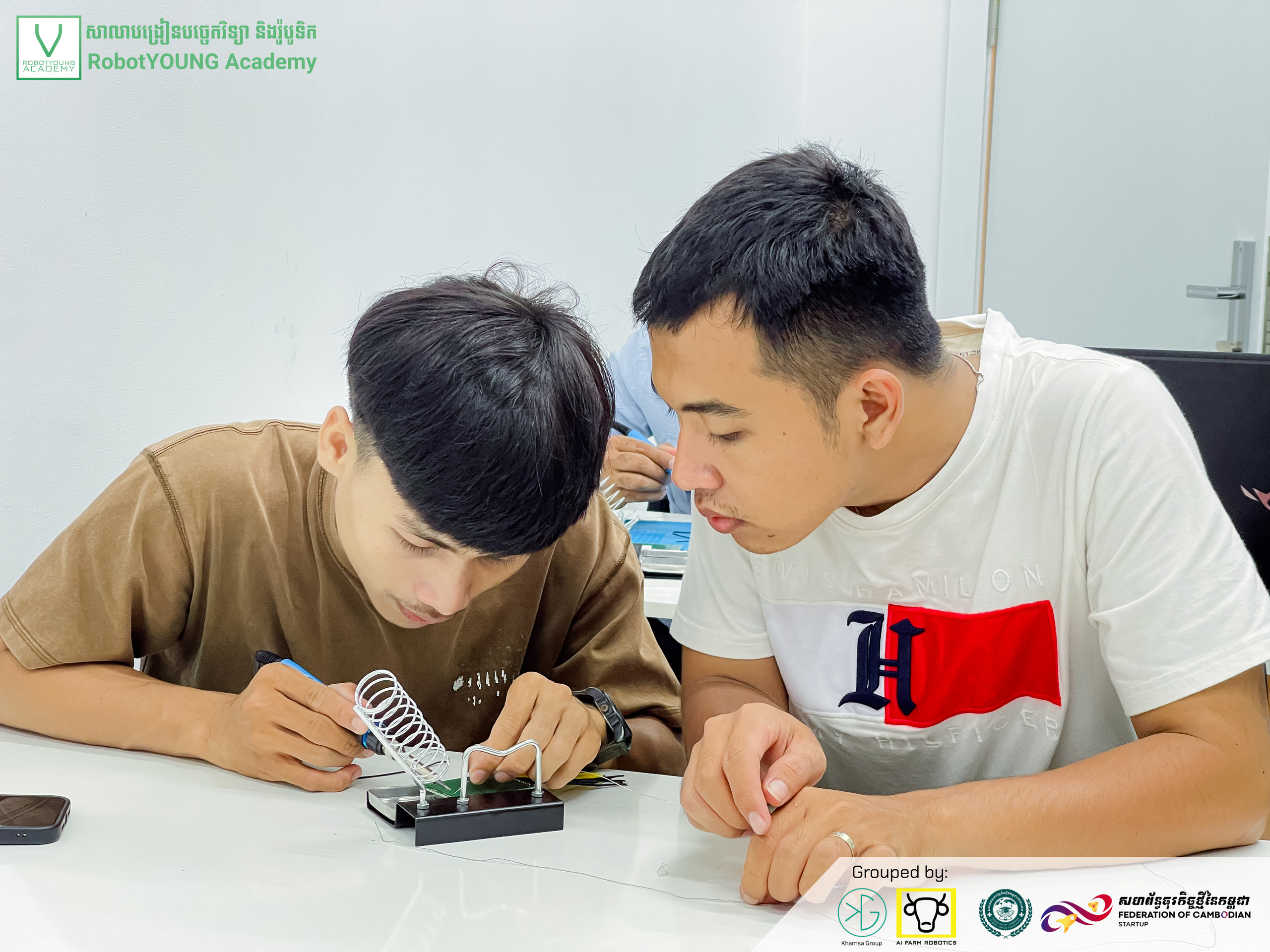 An adult guiding a student working on a circuit board
