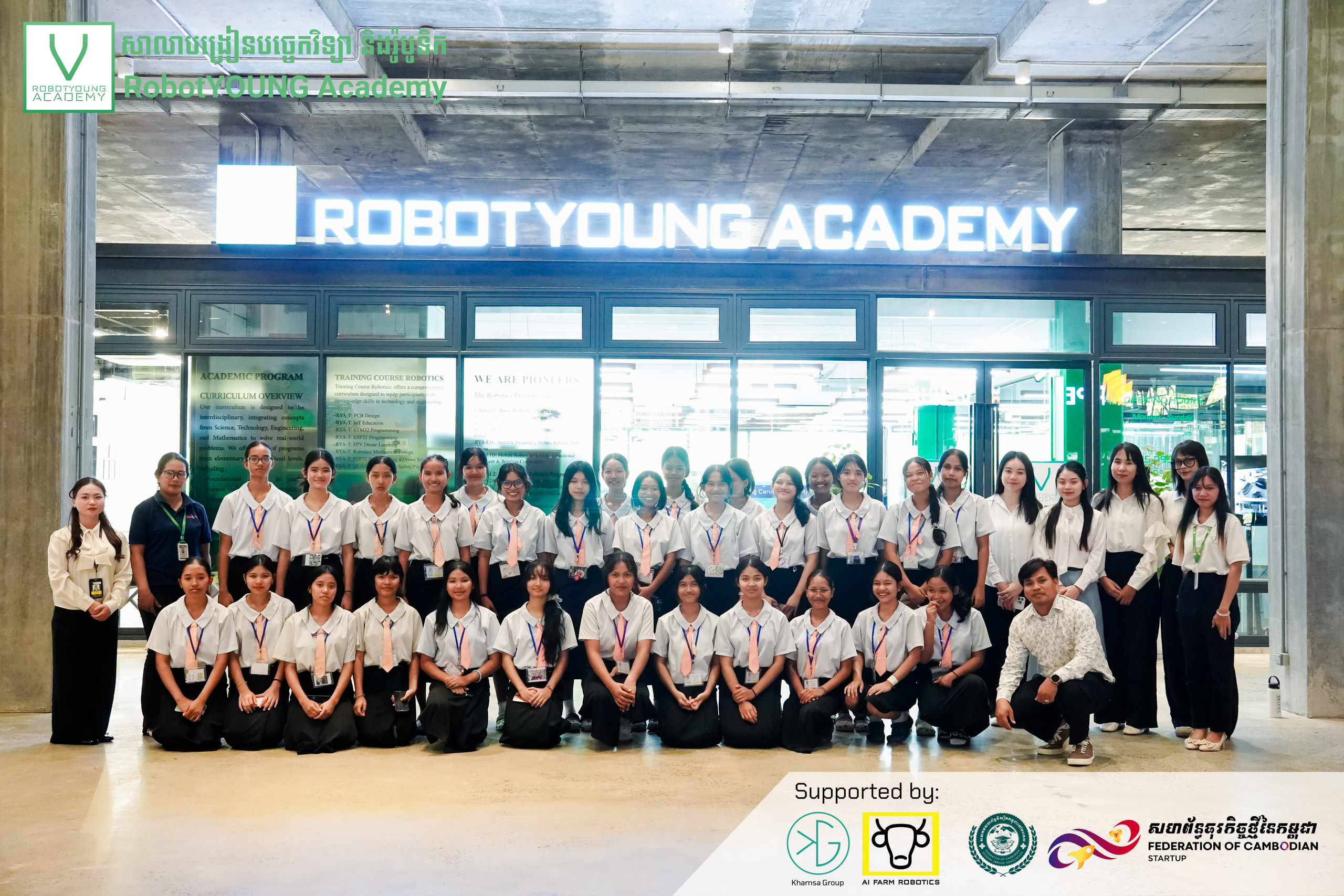 A large group posing in two rows outside the RobotYOUNG Academy entrance
